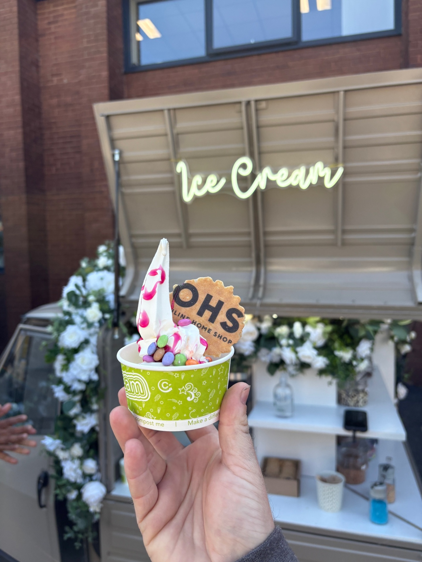 A cup of soft-serve ice cream with sprinkles and toppings