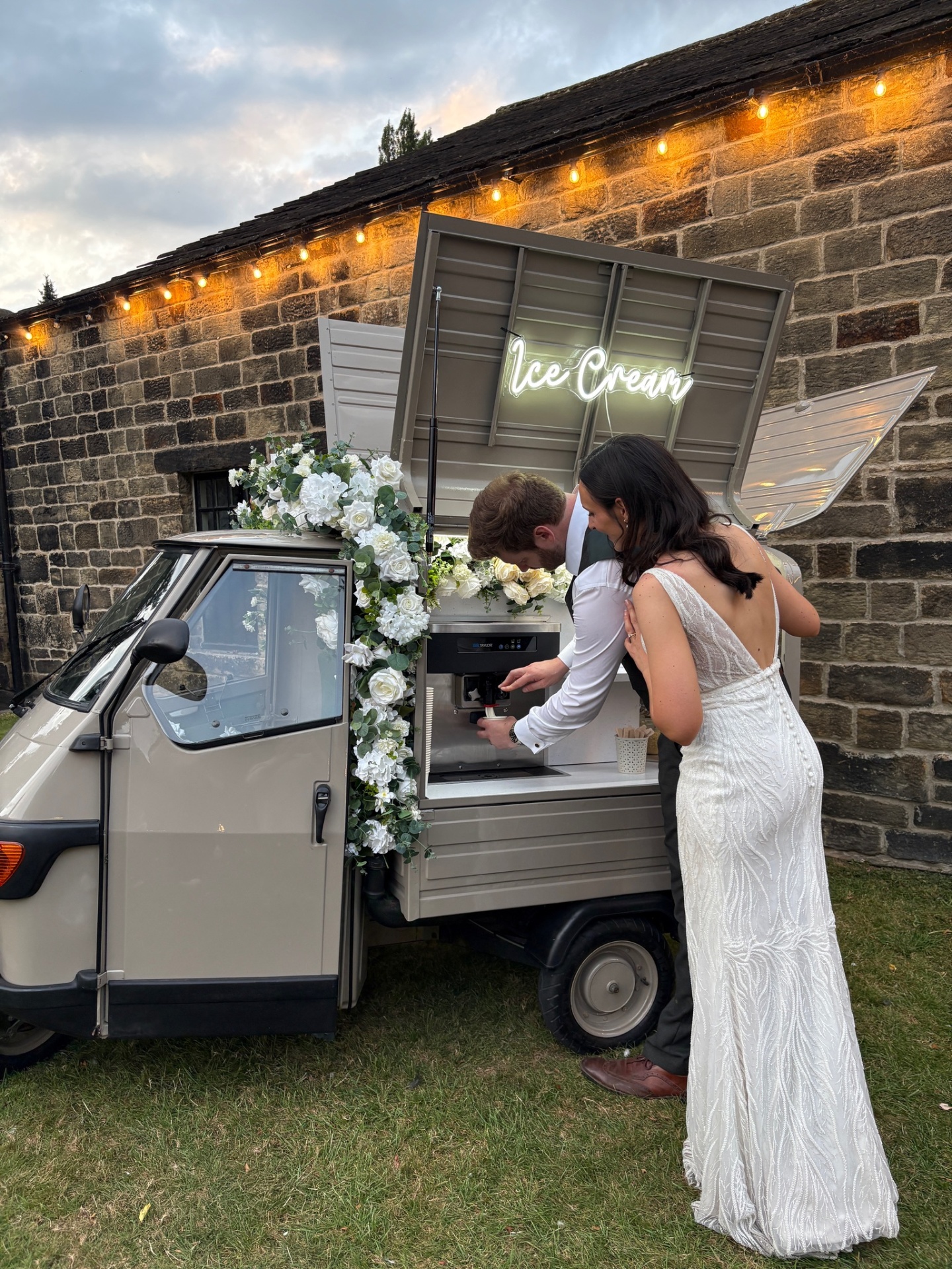 Couple serving soft-serve ice cream from the tuk-tuk at a wedding