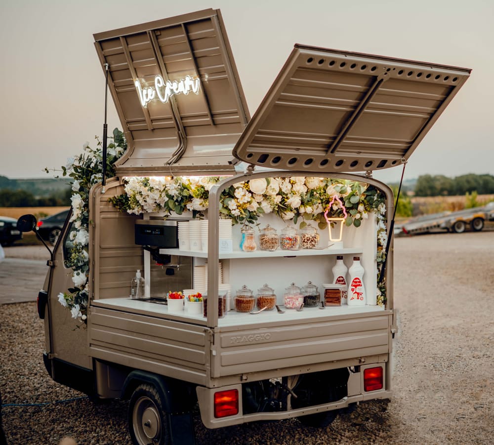 The vintage floral tuk-tuk set up for ice cream cart hire at a wedding venue