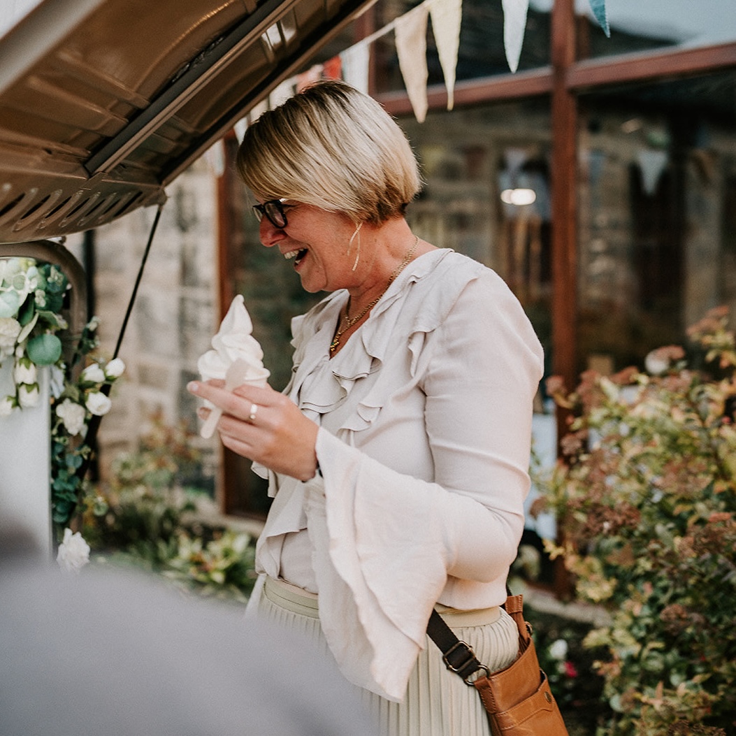 Guest smiling while enjoying a soft-serve ice cream cone from the tuk-tuk